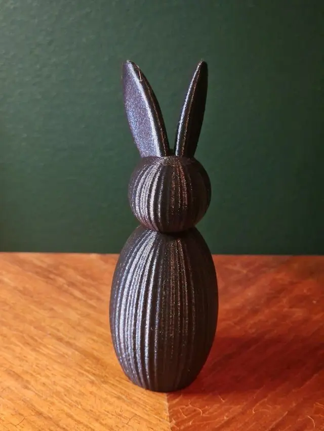 Musta 3D-tulostettu pupuhahmo puupöydällä